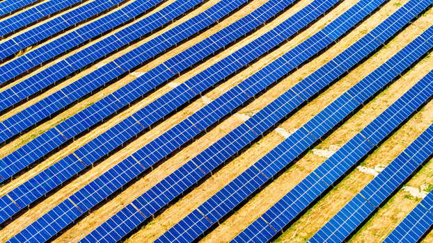 Aerial view of a modern solar park with rows of photovoltaic panels arranged in a field in Germany.