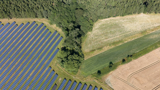 Aerial view of a solar farm with rows of photovoltaic panels situated next to a dense forest and agricultural fields in Atherstone England United Kingdom. Aerial view of a solar farm with rows of photovoltaic panels situated next to a dense forest and agricultural fields in Atherstone England United Kingdom.