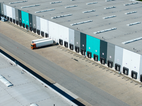 Aerial view of a large modern warehouse with numerous loading docks and a semi truck parked in the logistics yard in Lielvarzi Kekava Municipality Latvia. Aerial view of a large modern warehouse with numerous loading docks and a semi truck parked in the logistics yard in Lielvarzi Kekava Municipality Latvia.