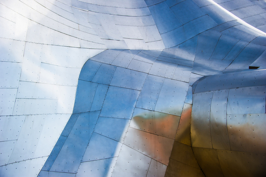 View of the metallic curved and riveted exterior facade of the Museum of Pop Culture reflecting the sky in Seattle Washington United States.