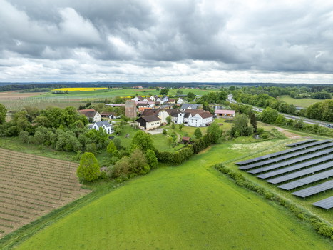 Aerial view of Aiglsbach village featuring the church tower solar panels and lush green fields under a cloudy sky Aiglsbach Bavaria Germany. Aerial view of Aiglsbach village featuring the church tower solar panels and lush green fields under a cloudy sky Aiglsbach Bavaria Germany.