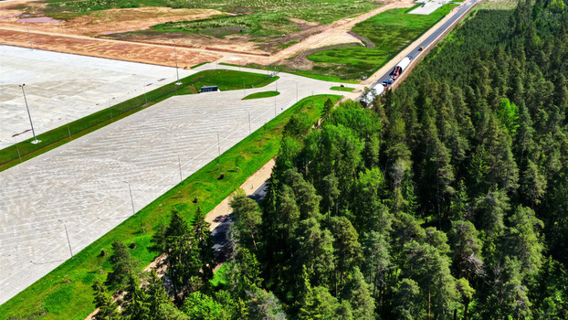 Aerial view of a large paved industrial area adjacent to a dense pine forest in Latvia. Aerial view of a large paved industrial area adjacent to a dense pine forest in Latvia.