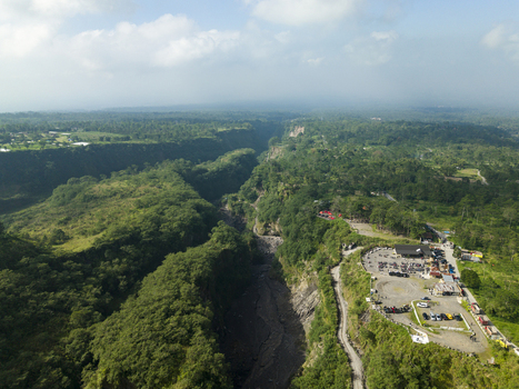Aerial view of Tambang Pasir Merapi Kali Gendol Sand Mine with deep river valley surrounded by lush green forest and parking area Kecamatan Cangkringan Daerah Istimewa Yogya Indonesia. Aerial view of Tambang Pasir Merapi Kali Gendol Sand Mine with deep river valley surrounded by lush green forest and parking area Kecamatan Cangkringan Daerah Istimewa Yogya Indonesia.