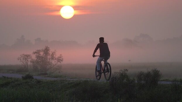 View of a person riding a bicycle at sunrise Bangladesh. View of a person riding a bicycle at sunrise Bangladesh.