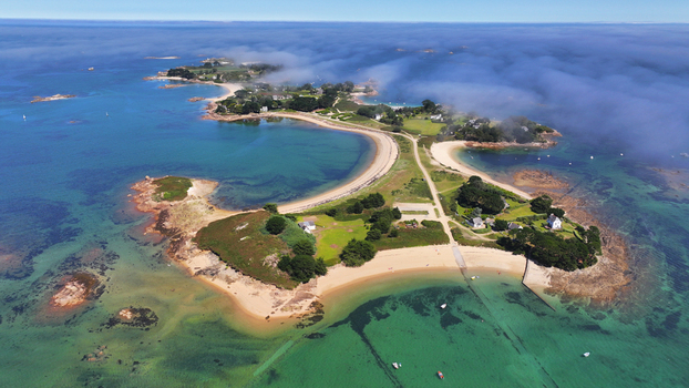 Aerial view of Callot island where the turquoise waters meet the rugged coastline a haven of serene beauty under a misty sky Carantec Brittany France.