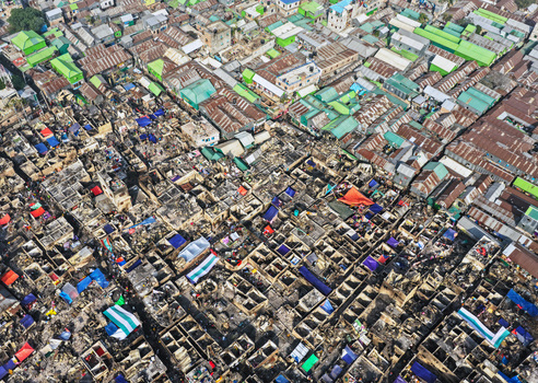 Aerial view of the fire damaged Korail Basti slum with charred structures and colorful tarps in the dense urban landscape of Dhaka Dhaka Division Bangladesh.
