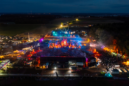 Herzogenaurach Germany 24 July 2025 Aerial view of the Open Beatz Festival featuring vibrant stage lights a large crowd of people and a Ferris wheel at night.