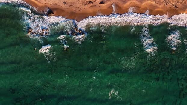 Aerial view of waves crashing on the sandy beach of Costa Paradiso Italy. Aerial view of waves crashing on the sandy beach of Costa Paradiso Italy.