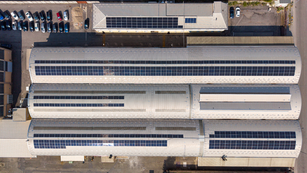 Aerial view of an industrial building featuring extensive rooftop solar panels clean metal roofing and a parking area with cars in Milan Lombardy Italy.