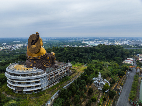Aerial view of the large golden Buddha statue at the Fo Guang Shan Buddha Museum surrounded by lush greenery and temple architecture in Jiuru Township Pingtung County Taiwan. Aerial view of the large golden Buddha statue at the Fo Guang Shan Buddha Museum surrounded by lush greenery and temple architecture in Jiuru Township Pingtung County Taiwan.