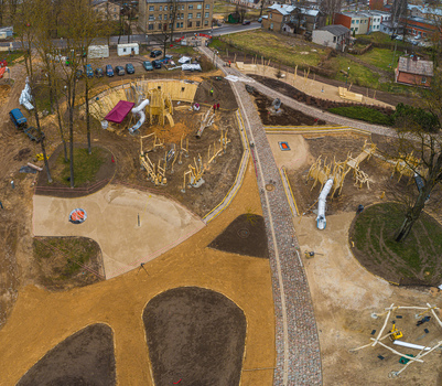 Aerial view of a wooden playground under construction with slides sand pits and walking paths surrounded by trees and residential buildings in Latvia. Aerial view of a wooden playground under construction with slides sand pits and walking paths surrounded by trees and residential buildings in Latvia.