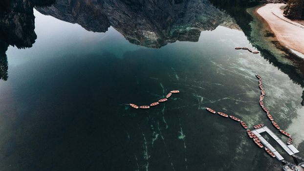 Aerial view of Lake Braies with wooden boats floating on the emerald water and mountain reflections on the surface in Braies Trentino Alto Adige Italy. Aerial view of Lake Braies with wooden boats floating on the emerald water and mountain reflections on the surface in Braies Trentino Alto Adige Italy.
