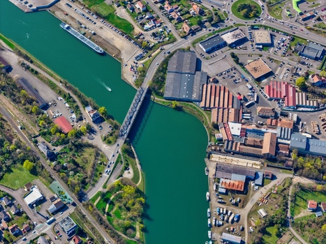 Aerial view of the shimmering canal waters reflecting the sky contrasting with the industrial buildings and the greenery of the nearby parks Sausheim Grand Est France.