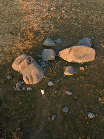 Aerial view of weathered boulders scattered across a grassy landscape their surfaces catching the warm glow of the setting sun Nasbinals Occitanie France. Aerial view of weathered boulders scattered across a grassy landscape their surfaces catching the warm glow of the setting sun Nasbinals Occitanie France.