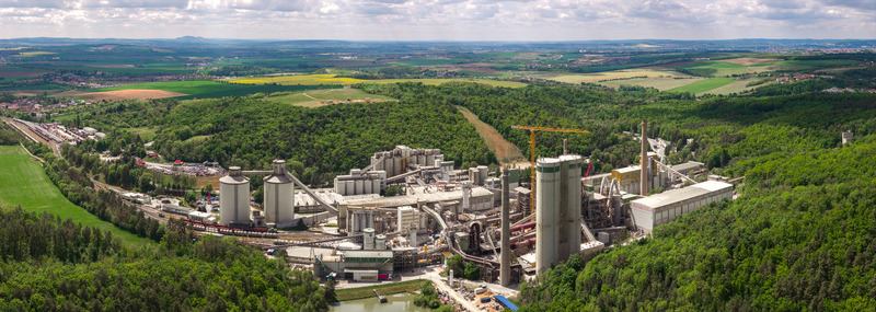 Aerial view of a large cement plant with tall silos and industrial structures surrounded by lush green forests and rolling hills in Mokra Horakov Jihomoravsky kraj Czechia. Aerial view of a large cement plant with tall silos and industrial structures surrounded by lush green forests and rolling hills in Mokra Horakov Jihomoravsky kraj Czechia.