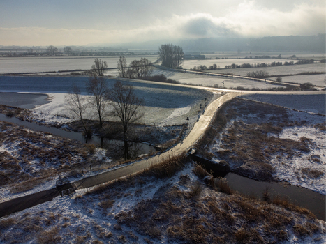 Aerial view of a road cutting through the snow dusted fields near Vlietberg with a bridge over a meandering stream Tiengeboden Gelderland Netherlands. Aerial view of a road cutting through the snow dusted fields near Vlietberg with a bridge over a meandering stream Tiengeboden Gelderland Netherlands.