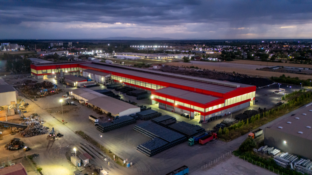 Aerial view of a large industrial facility with red roofed warehouses storage yards filled with metal pipes and trucks parked at night in Sremska Mitrovica Vojvodina Serbia. Aerial view of a large industrial facility with red roofed warehouses storage yards filled with metal pipes and trucks parked at night in Sremska Mitrovica Vojvodina Serbia.