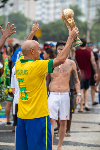 Rio de Janeiro Brazil 13 June 2026 View of a football fan in a yellow Brazil jersey holding a replica of the World Cup trophy amidst a crowd on a mosaic street during the World Cup 2026.