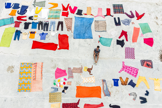 Dinajpur District Bangladesh 26 July 2026 Aerial view of Jharbari Bazar with a person sitting on a concrete surface surrounded by colorful clothes laid out to dry.