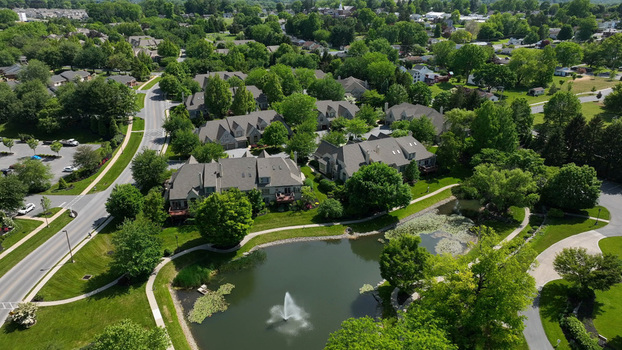 Aerial view of a retirement community campus in West Lampeter Township featuring residential buildings a pond with a fountain and lush trees in Willow Street Pennsylvania United States.