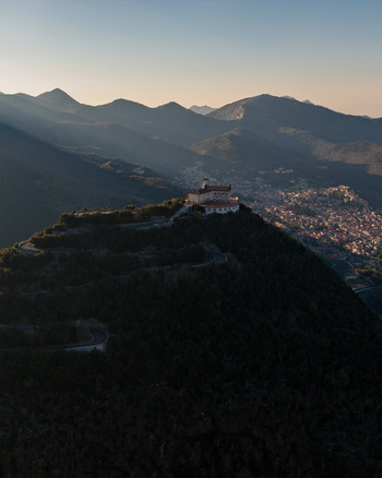 Aerial view of Santuario del Santissimo Salvatore perched on a mountain peak with winding roads and the town of Montella in the valley under golden hour light Montella Campania Italy. Aerial view of Santuario del Santissimo Salvatore perched on a mountain peak with winding roads and the town of Montella in the valley under golden hour light Montella Campania Italy.