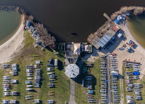 Aerial view of boats lined up neatly on the grassy shore near a marina with sandy beaches meeting the dark water Almere Flevoland Netherlands. Aerial view of boats lined up neatly on the grassy shore near a marina with sandy beaches meeting the dark water Almere Flevoland Netherlands.