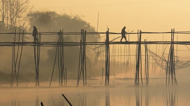 View of people walking on a bamboo bridge in Bogura Bangladesh.
