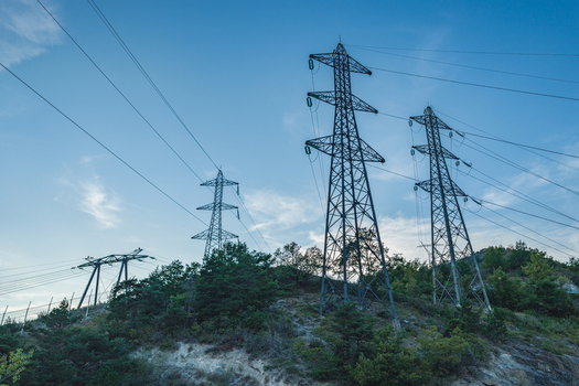 Aerial view of high voltage power transmission towers standing on a forested hillside in a mountainous landscape in Rousset Serre Poncon Provence Alpes Cote d Azur France.