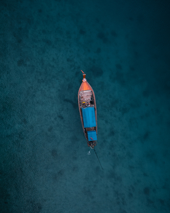 Aerial view of a traditional Thai long tail boat floating on the clear turquoise waters of Pi Leh Bay Tambon Ao Nang Chang Wat Krabi Thailand. Aerial view of a traditional Thai long tail boat floating on the clear turquoise waters of Pi Leh Bay Tambon Ao Nang Chang Wat Krabi Thailand.