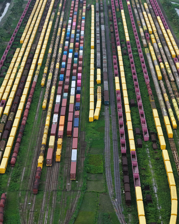 Aerial view of the Chattogram Port train yard featuring rows of colorful cargo containers on rail cars with green vegetation between tracks in Chittagong Chittagong Division Bangladesh.