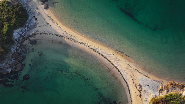 Aerial view of the sandy isthmus connecting rocky outcrops amidst the shimmering emerald and turquoise waters Carantec Brittany France. Aerial view of the sandy isthmus connecting rocky outcrops amidst the shimmering emerald and turquoise waters Carantec Brittany France.