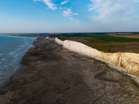 Aerial view of the Beach of the Bois de Cise featuring dramatic white chalk cliffs rocky shoreline and green fields along the coast in Ault Hauts de France France.