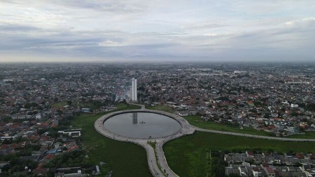 Aerial view of the circular lake and tall building in Summarecon Bekasi surrounded by dense urban residential areas in Bekasi Barat West Java Indonesia. Aerial view of the circular lake and tall building in Summarecon Bekasi surrounded by dense urban residential areas in Bekasi Barat West Java Indonesia.