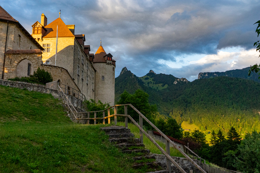 Gruyeres Switzerland 14 May 2026 View of Chateau de Gruyeres with its medieval stone walls and orange tiled roofs overlooking lush green mountains under a dramatic sunset sky. Gruyeres Switzerland 14 May 2026 View of Chateau de Gruyeres with its medieval stone walls and orange tiled roofs overlooking lush green mountains under a dramatic sunset sky.