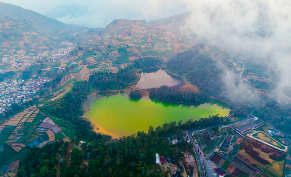 Aerial view of Telaga Warna Dieng with its vibrant green and dark volcanic lakes surrounded by terraced agricultural fields and misty hills in Kecamatan Kejajar Jawa Tengah Indonesia. Aerial view of Telaga Warna Dieng with its vibrant green and dark volcanic lakes surrounded by terraced agricultural fields and misty hills in Kecamatan Kejajar Jawa Tengah Indonesia.