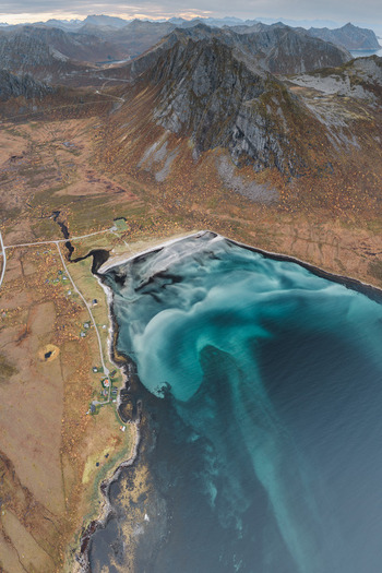 Aerial view of Senja island featuring dramatic mountains a turquoise sandy beach and coastal roads in Senja Troms Norway.