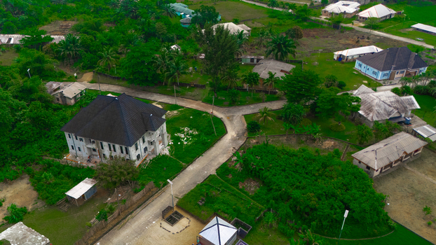 Aerial view of residential houses nestled among lush green trees and vegetation in a rural landscape in Minima Rivers Nigeria.