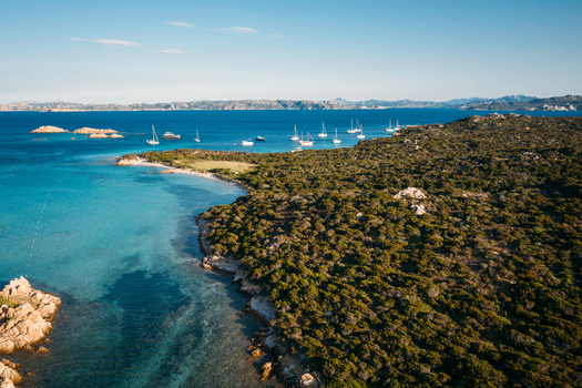Aerial view of group of boats anchored in the bay of Cala Santa Maria Sardinia Italy.