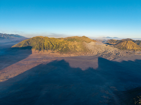 Aerial view of the volcanic landscape of Mount Bromo with its rugged caldera and dramatic shadows cast by the morning sun in Sukapura East Java Indonesia. Aerial view of the volcanic landscape of Mount Bromo with its rugged caldera and dramatic shadows cast by the morning sun in Sukapura East Java Indonesia.