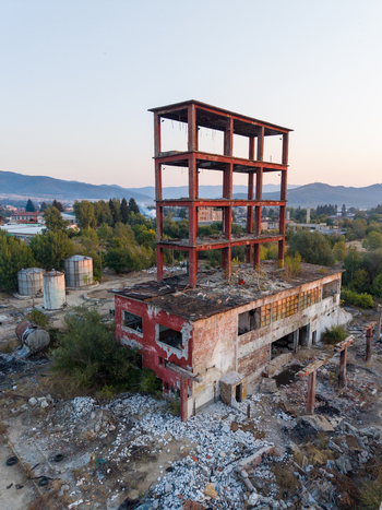 Aerial view of an abandoned industrial building with a prominent red steel frame structure surrounded by debris and scattered rubble in Velingrad Pazardzhik Bulgaria. Aerial view of an abandoned industrial building with a prominent red steel frame structure surrounded by debris and scattered rubble in Velingrad Pazardzhik Bulgaria.