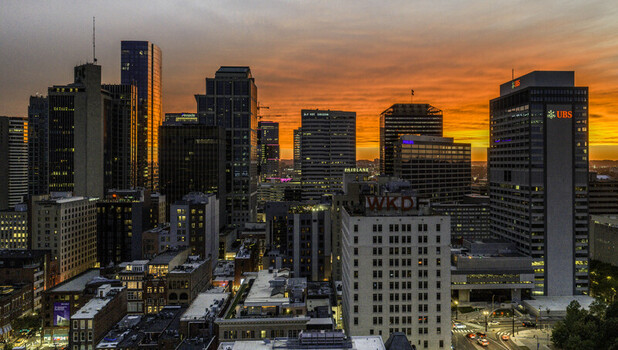 Aerial view of the downtown Nashville skyline at sunset featuring modern skyscrapers historic buildings and glowing city lights under a vibrant orange sky in Nashville TN United States.