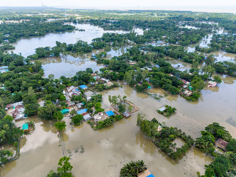Aerial view of the flooded landscape with houses partially submerged in water surrounded by lush green trees and vegetation in Banshkhali Upazila Chittagong Division Bangladesh. Aerial view of the flooded landscape with houses partially submerged in water surrounded by lush green trees and vegetation in Banshkhali Upazila Chittagong Division Bangladesh.