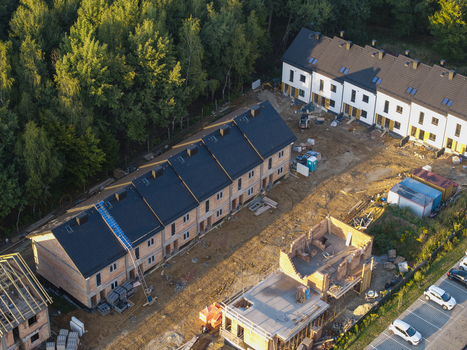 Aerial view of a residential construction site with rows of terraced houses in various stages of completion near trees and a parking area in Wieliczka Lesser Poland Voivode Poland.