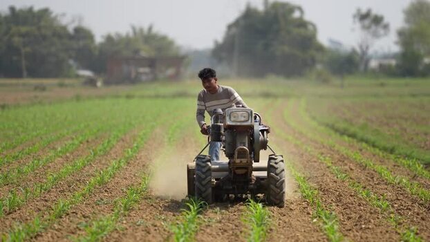 View of a farmer operating a power tiller in a field Nepal. View of a farmer operating a power tiller in a field Nepal.