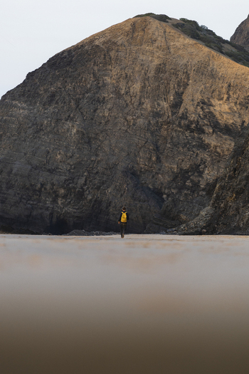 View of people walking on the yellow sandy beach with dramatic cliffs and rock formations Praia da Cordoama Sagres Portugal.