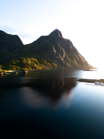 Aerial view of the majestic Tangstad mountain reflecting in the calm waters of a fjord during golden hour Leknes Nordland Norway. Aerial view of the majestic Tangstad mountain reflecting in the calm waters of a fjord during golden hour Leknes Nordland Norway.