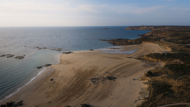 Aerial view of the rugged coastline featuring sandy beaches rocky outcrops and the distant Cap Frehel lighthouse along the Atlantic shore in Plevenon Brittany France. Aerial view of the rugged coastline featuring sandy beaches rocky outcrops and the distant Cap Frehel lighthouse along the Atlantic shore in Plevenon Brittany France.