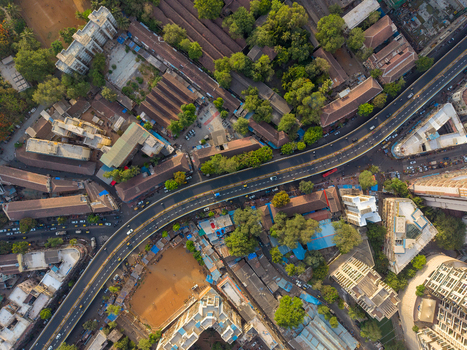 Aerial view of the dense urban landscape and elevated highway winding through the city with rooftops lush trees and traffic in Mumbai Maharashtra India. Aerial view of the dense urban landscape and elevated highway winding through the city with rooftops lush trees and traffic in Mumbai Maharashtra India.