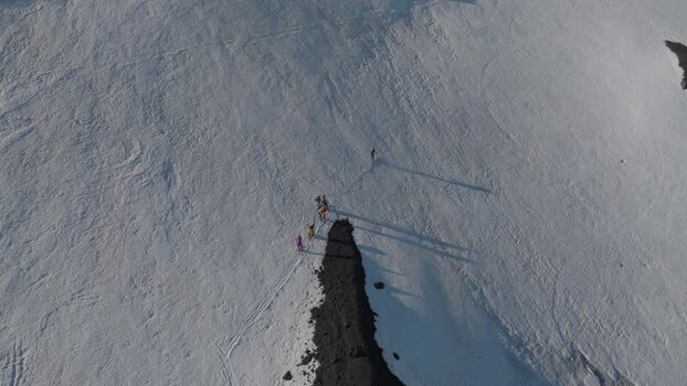 Aerial view of hikers trekking on snowy slopes of Mount Etna Italy. Aerial view of hikers trekking on snowy slopes of Mount Etna Italy.