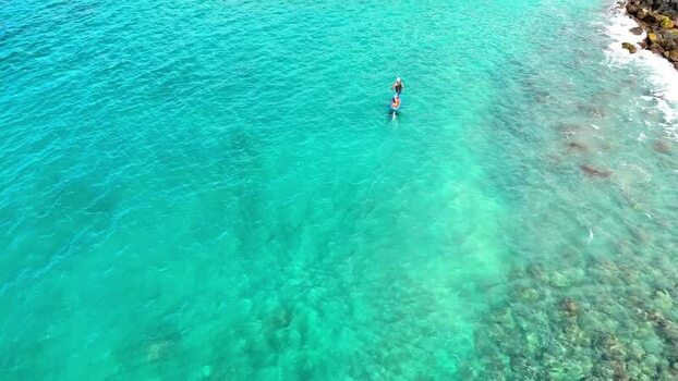 Aerial view of a person hydrofoiling in clear water United States. Aerial view of a person hydrofoiling in clear water United States.